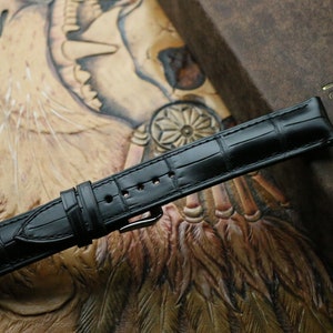 Close-up black alligator leather watch strap texture and stitching detail