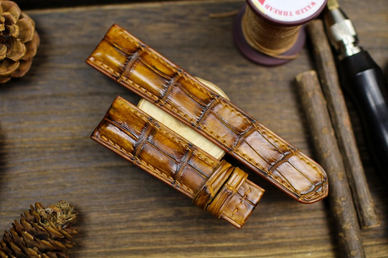 Tan patina alligator leather watch straps with crocodile texture on rustic wooden background - handmade vintage watch bands