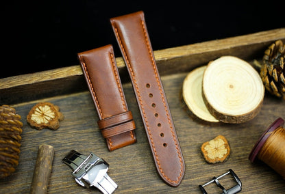 Brown Vachetta leather watch straps with deployant clasp on rustic wooden background - handmade Italian leather watch bands